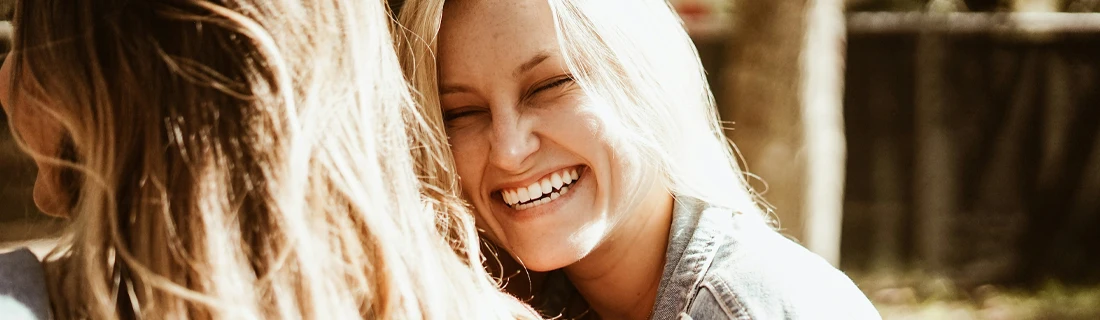 Dentist Feeding Hills MA Dental Bridges Focused Woman grinning and laughing with her friend displaying her beautiful teeth