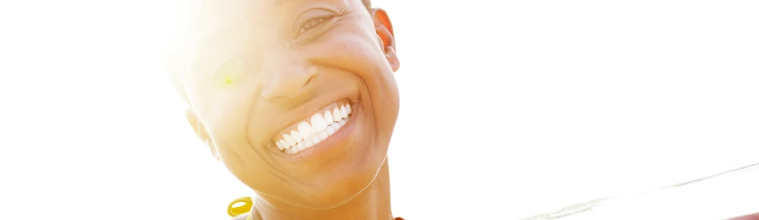 Dentist Feeding Hills MA Invisalign Focused A beautiful woman with short hair is outside in the sun while smiling at the camera